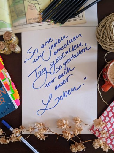 Eine handgeschriebene Notiz auf Papier mit blauer Tinte und dekorativen Elementen.