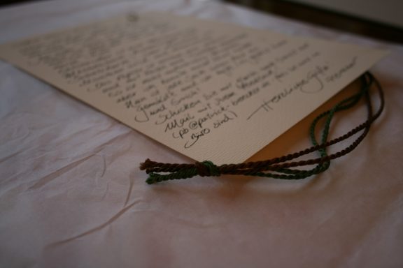 Alter Brief mit handgeschriebener Nachricht und geflochtenem Band auf einem Tisch.